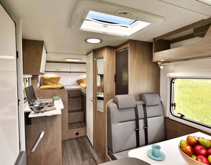 Intérieur d’un camping-car Carado avec salon, cuisine, lanterneau et lits simples à l’arrière