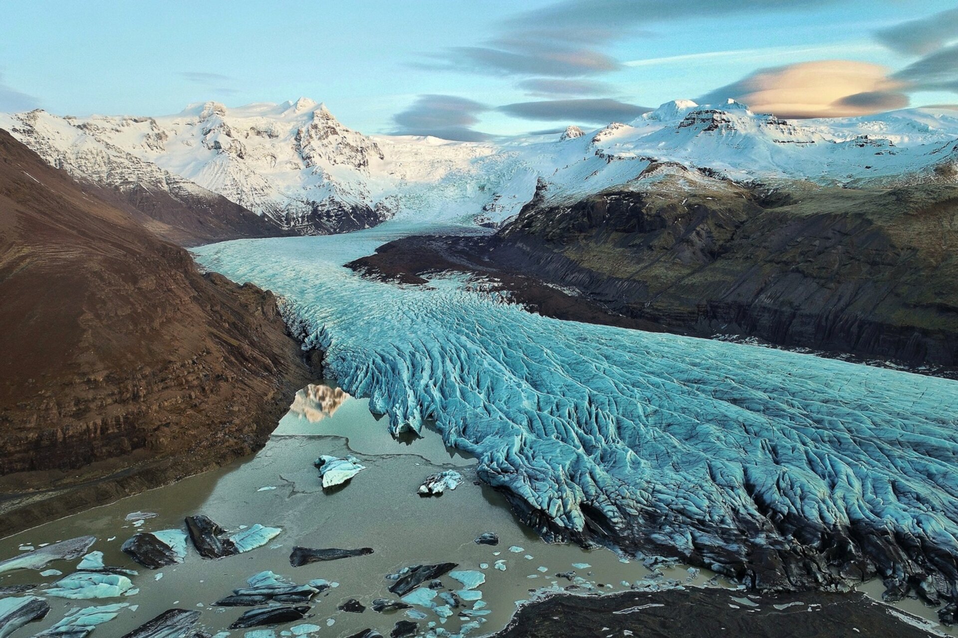 Vue d'un paysage originel avec glace, neige et montagnes sous un ciel légèrement nuageux, photographié lors d'un voyage en camping-car en Islande.