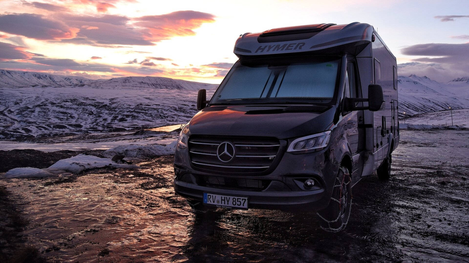Un camping-car est stationné au coucher du soleil dans un environnement enneigé. Photographié lors d'un voyage en Islande en camping-car après le ferry.