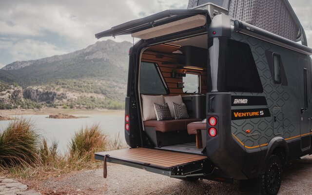 Utsikt från baksidan av Venture S, med taket och Sunset Deck utfoldat, med fjell och vann i bakgrunnen.