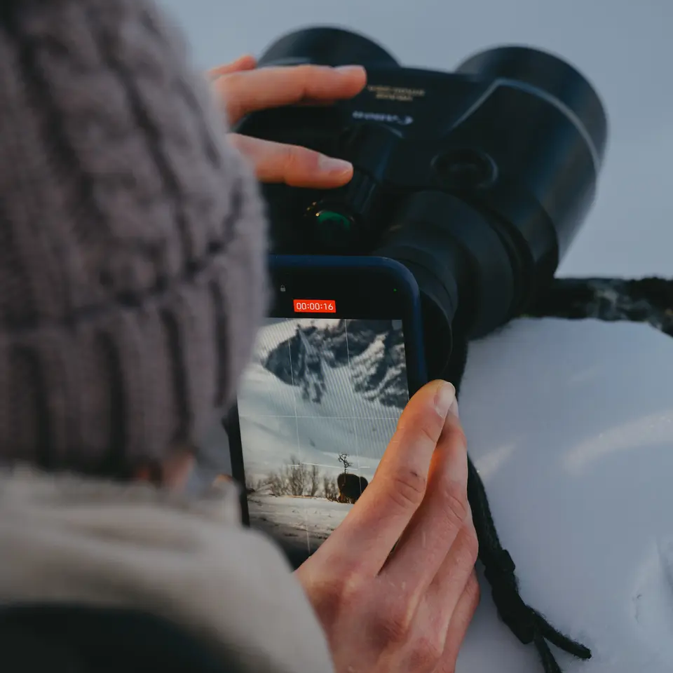 Vrouw filmt met haar telefoon door een verrekijker
