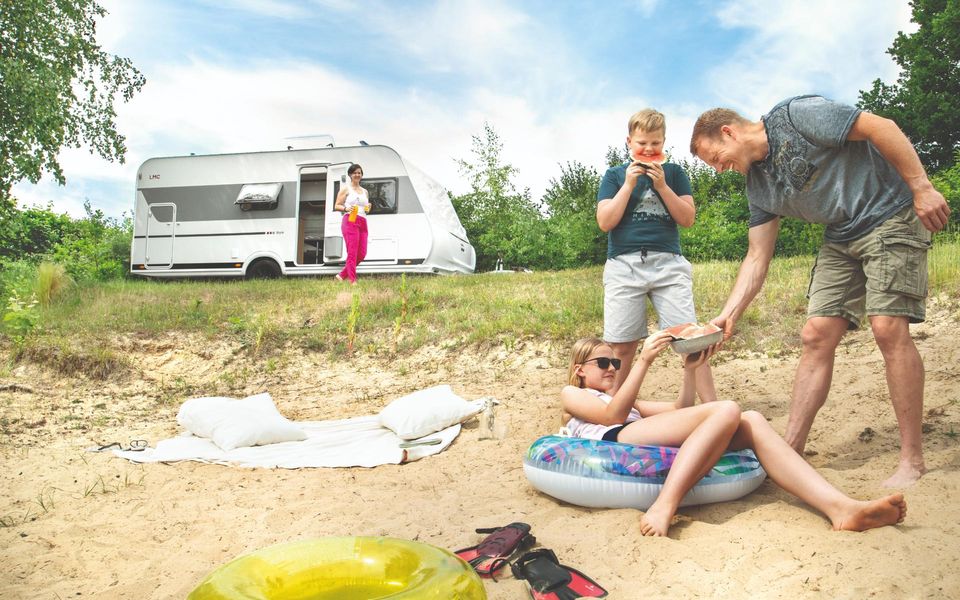 Das Bild zeigt eine Familie vor dem LMC Wohnwagen Style.